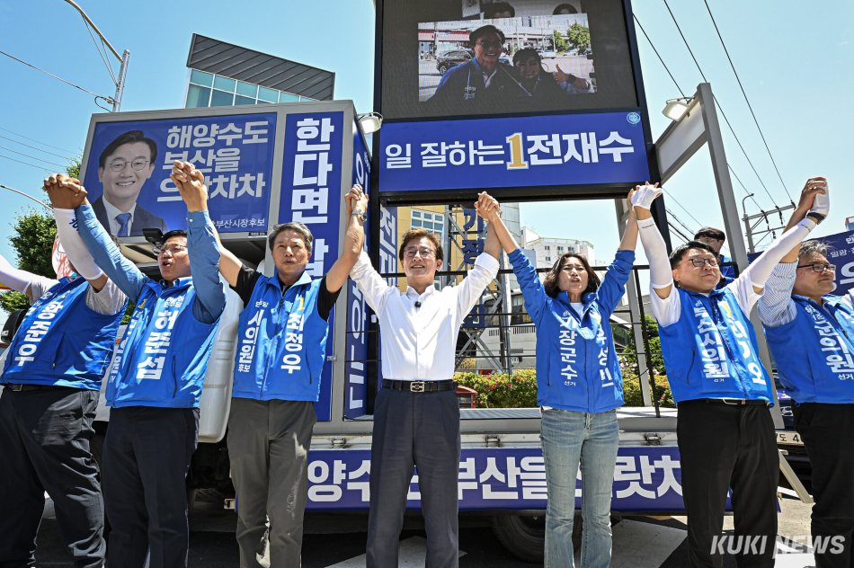 전재수 더불어민주당 부산시장 후보가 30일 부산 기장군 기장시장 인근 유세에서 부산시의원·기장군의원 후보들과 함께 두 손을 들어 인사하고 있다.