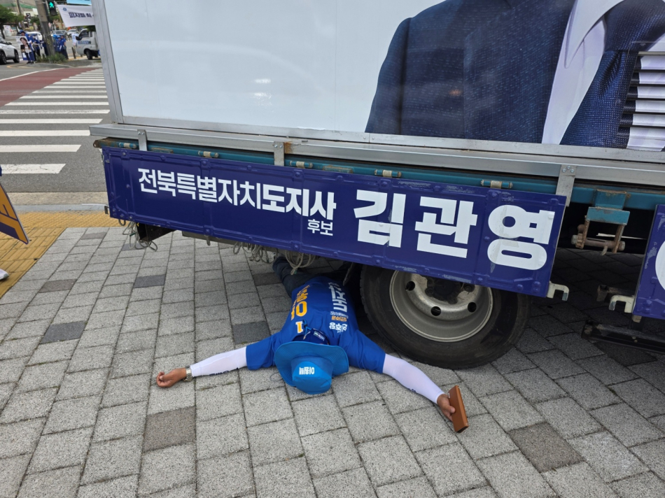 이원택 더불어민주당 전북도지사 후보의 선거운동원이 1일 오전 8시30분쯤 전북 전주시 완산구 효자동의 한 사거리에 주차된 김관영 무소속 후보의 차량 아래 들어가 누워 있다. 김관영 후보 캠프 제공
