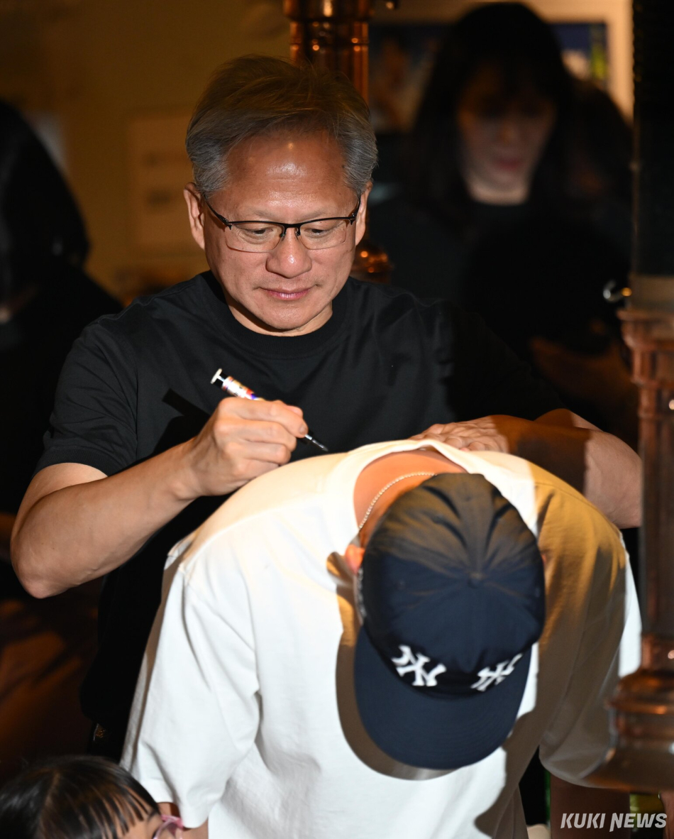 젠슨 황 엔비디아 최고경영자(CEO)가 5일 서울 마포구 서교동의 한 고깃집에서 열린 최태원 SK회장, 구광모 LG회장, 이해진 네이버 의장과의 삼겹살 회동 중 한 시민의 등에 사인하고 있다.