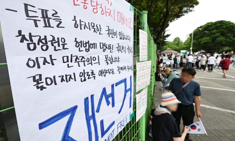 6·3 지방선거 투표지 부족 사태를 규탄하며 재선거를 요구하는 잠실 개표소 봉쇄 시위가 계속되고 있는 7일 서울 송파구 올림픽공원 핸드볼경기장 출입구 앞에 재선거를 요구하는 문구 등이 적힌 종이가 붙어있다. 연합뉴스